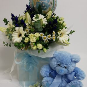 flower display with a blue teddy bear